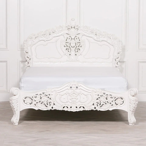 White ornate carved bed frame with intricate headboard and footboard, classic bedroom style