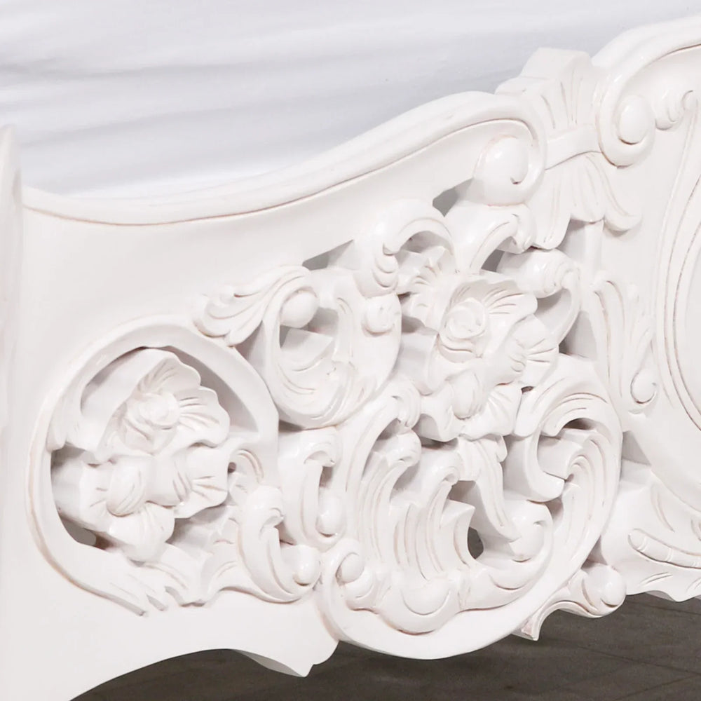 White carved wood bed frame with ornate floral detailing