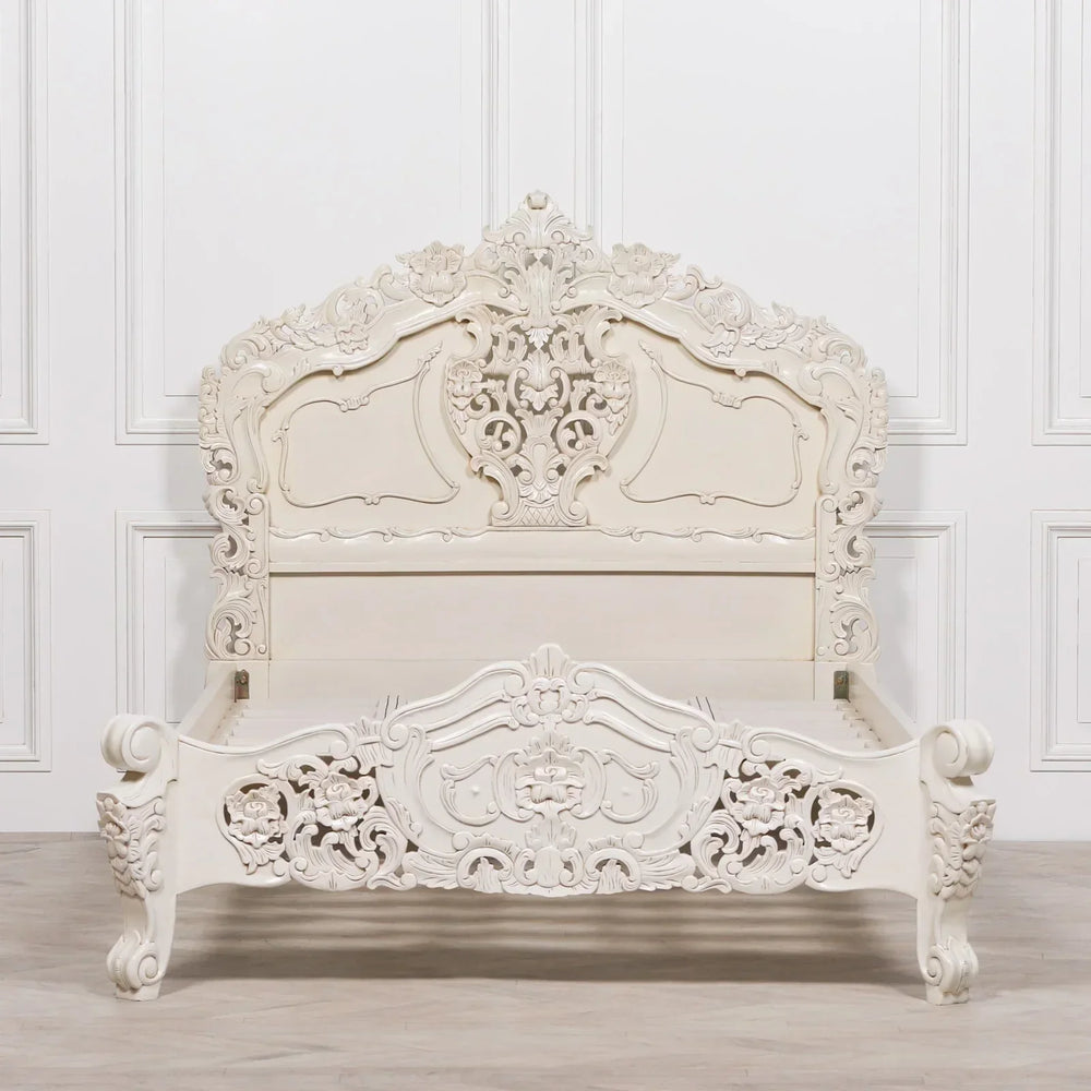 Ornate carved wood bed frame in white finish with detailed floral patterns and high headboard