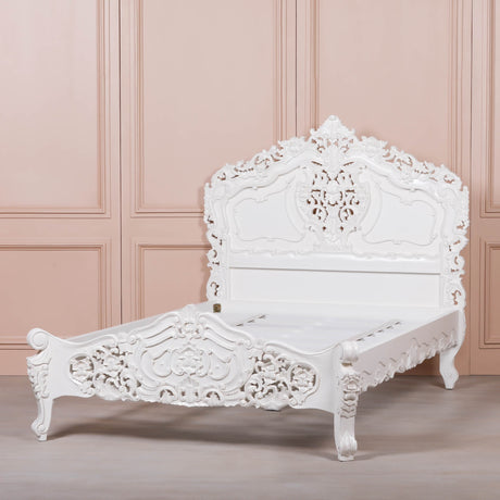 White ornate bed against a pink paneled wall