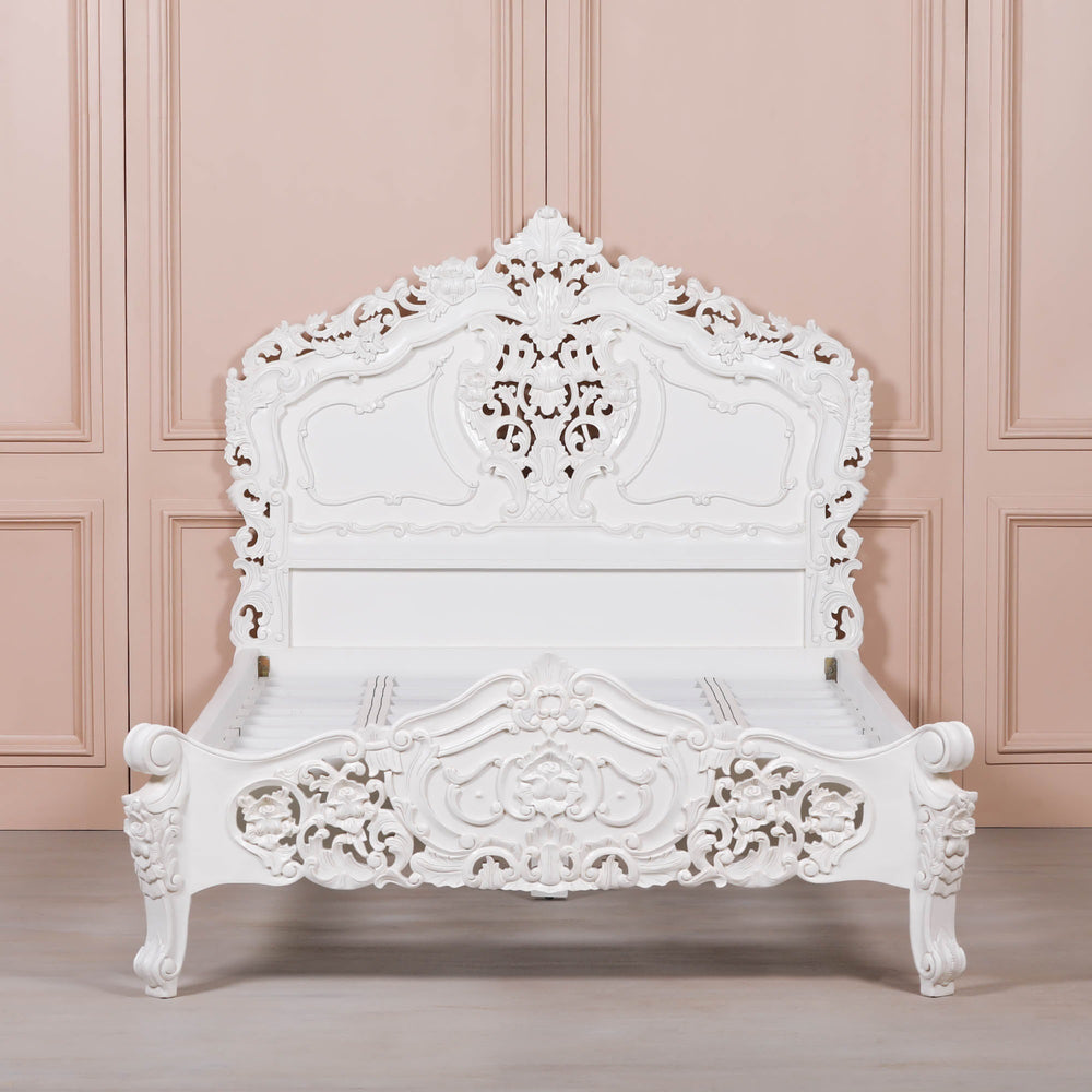 White ornate bed against a pink paneled wall