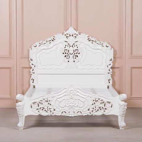 White ornate bed against a pink paneled wall