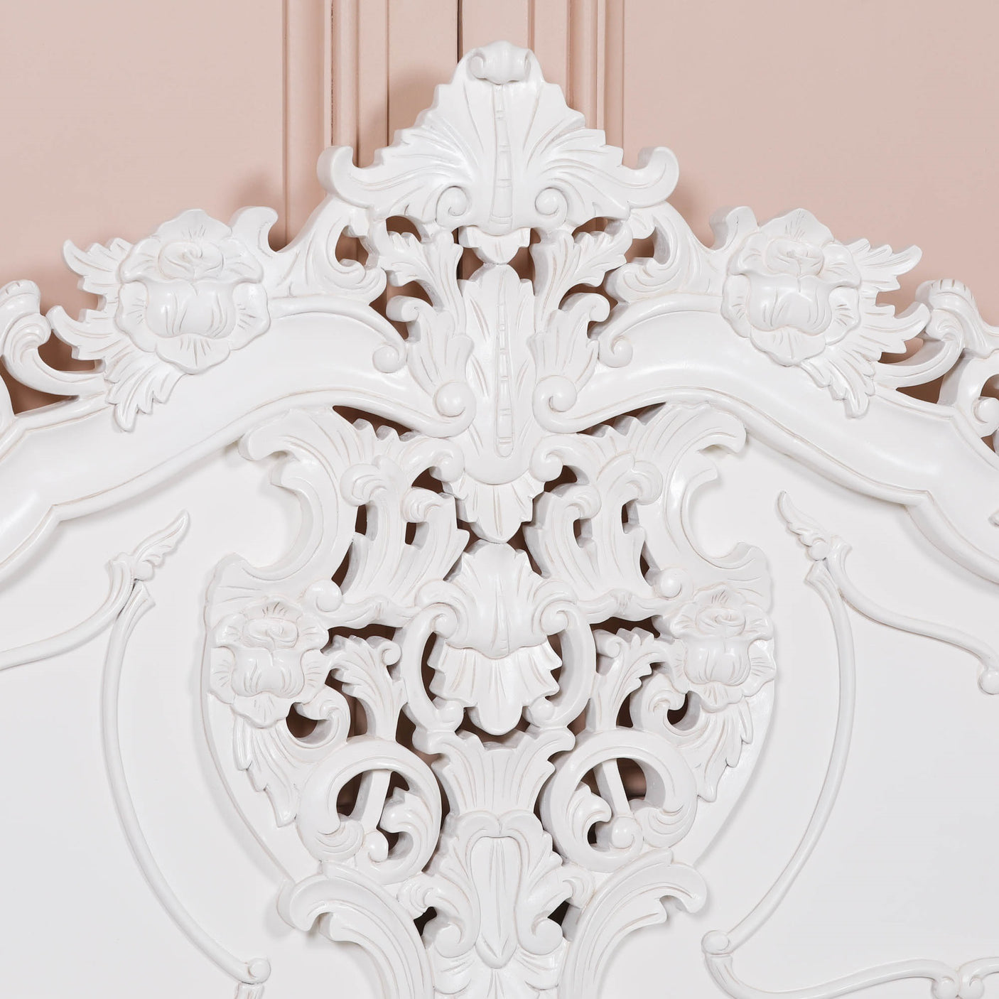 Close-up of an ornate white decorative wall piece against a pink background
