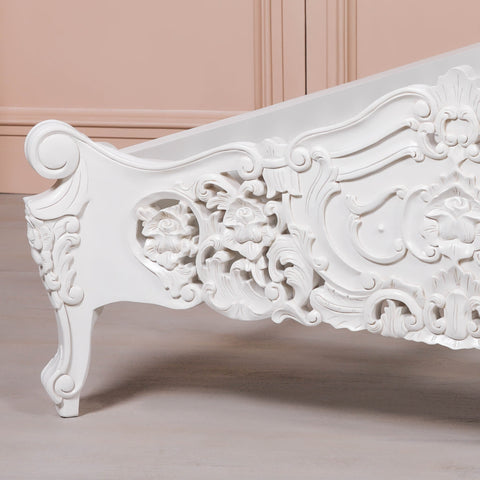 Decorative white bed with intricate carvings on a beige background