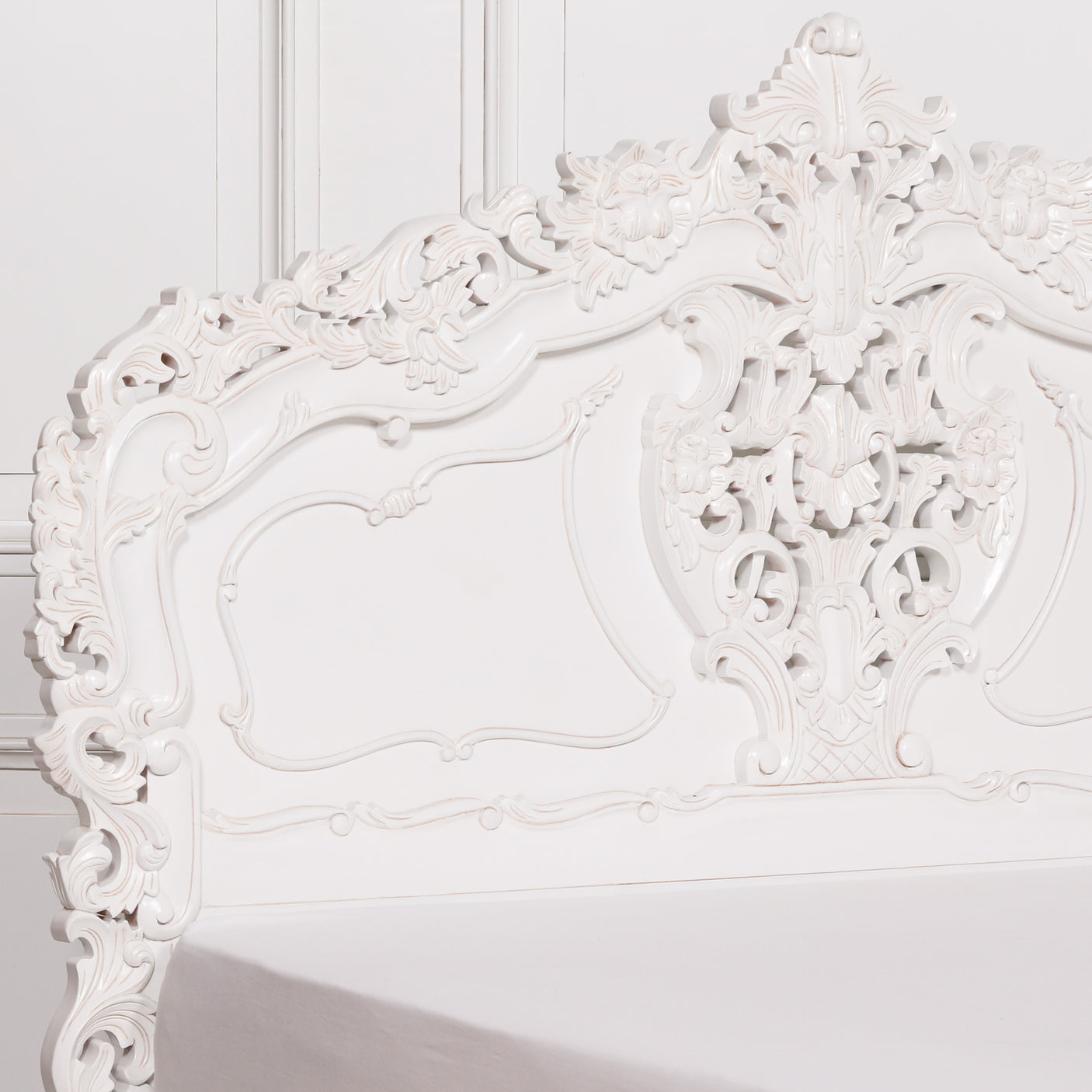 Ornate white headboard on a white wall