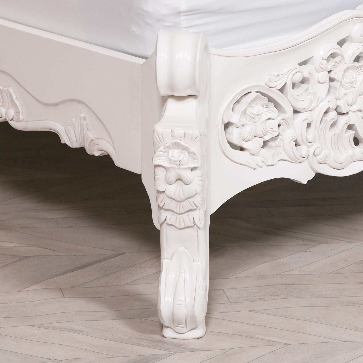 Carved white wooden table with intricate designs on a wooden floor.