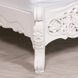 Carved white wooden table with intricate designs on a wooden floor.