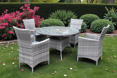 Grey rattan dining set with round glass table and four chairs on garden lawn