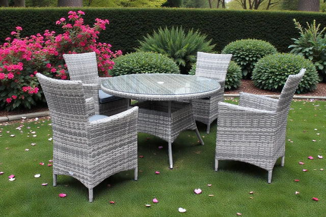 Grey rattan dining set with round glass table and four chairs on garden lawn