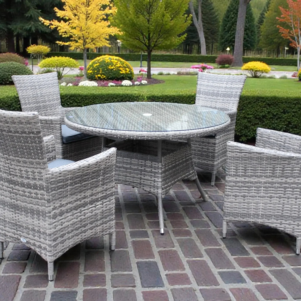 Grey rattan dining set with round glass table and four chairs on patio in garden setting