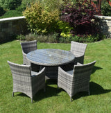 Rattan outdoor dining set with round glass table and four armchairs on garden lawn