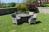 Grey rattan dining set with glass top table and five chairs on lawn in garden setting
