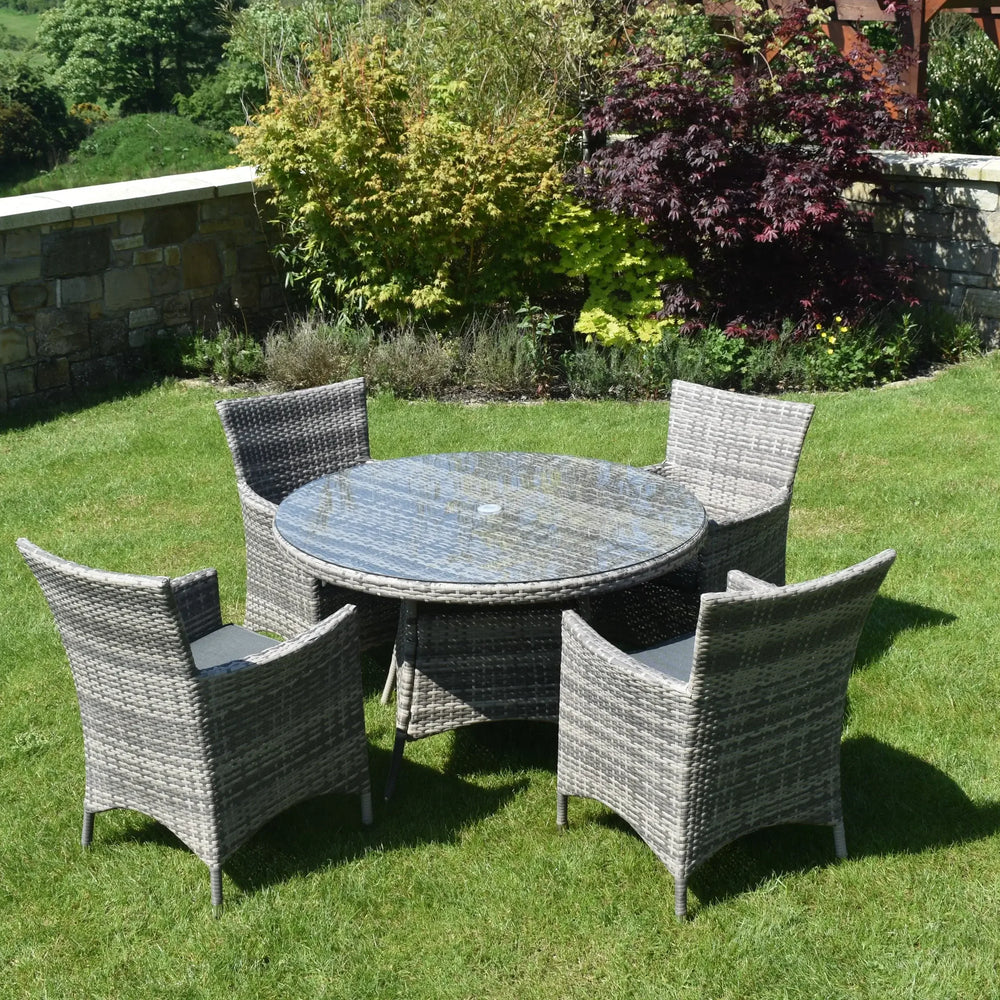 Grey rattan outdoor dining set with glass-top round table and four chairs on garden lawn