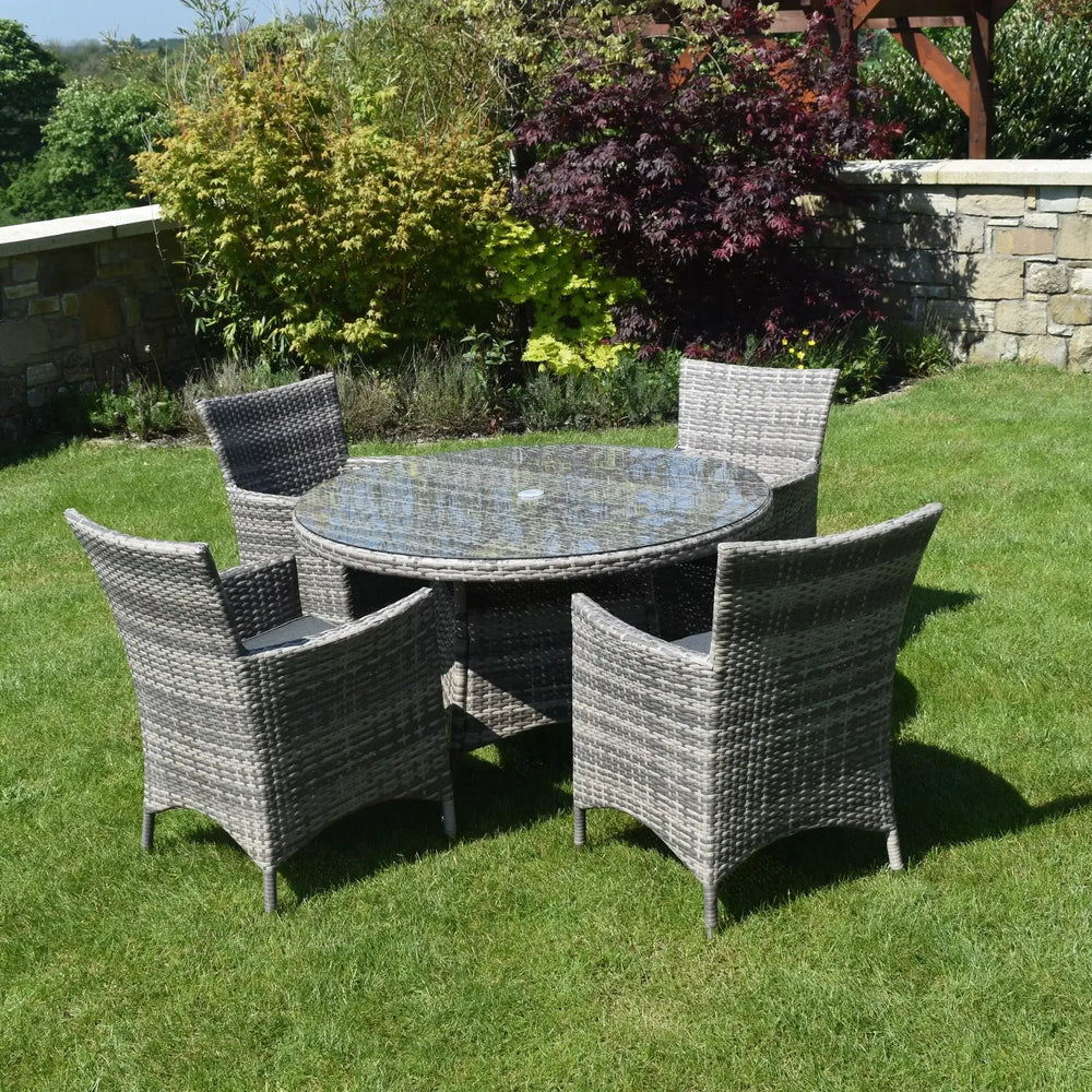 Grey rattan dining set with round glass table and four chairs on garden lawn