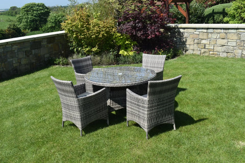 Grey rattan dining set with round glass table and four chairs on garden lawn