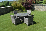 Grey rattan dining set with round glass table and four chairs on garden lawn