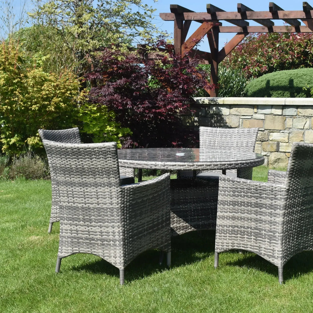 Rattan dining set with round glass table and four chairs on green lawn