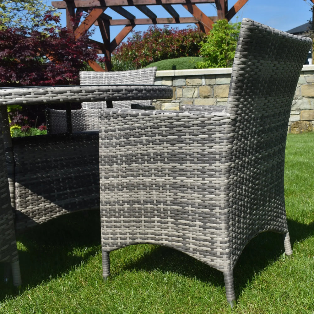 Grey rattan outdoor dining set with chairs and round table on grass garden lawn