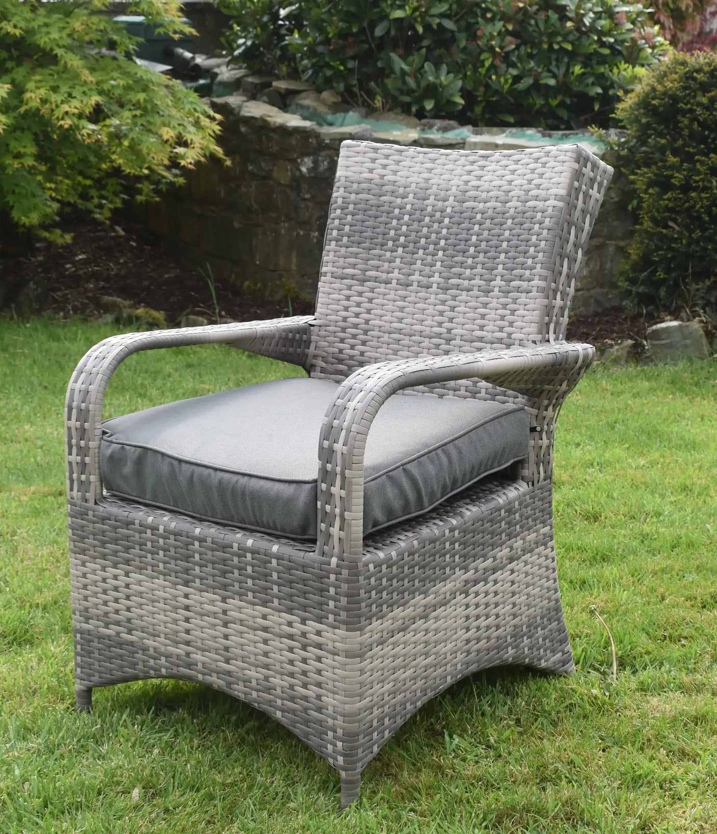 Grey rattan garden dining chair with cushion on lawn
