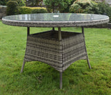 Round rattan outdoor dining table with glass top on grass garden lawn
