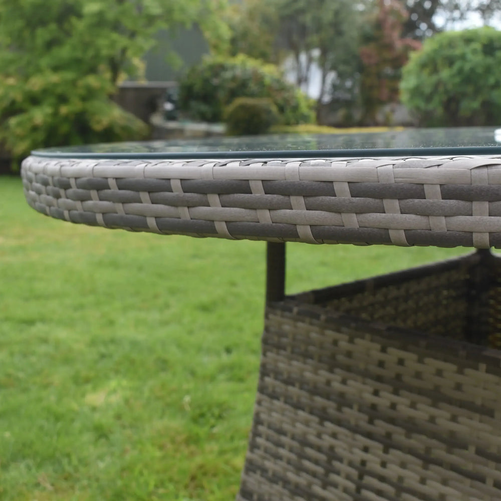 Close-up of rattan outdoor dining table with glass top on lawn