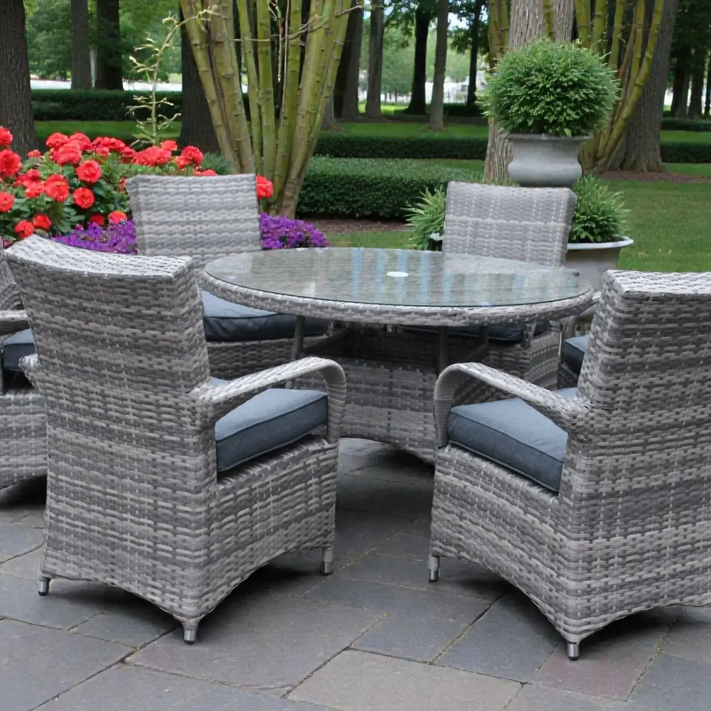 Grey rattan garden dining set with round glass table and cushioned chairs on patio