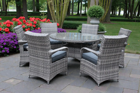 Grey rattan garden dining set with round glass table and cushioned chairs on patio