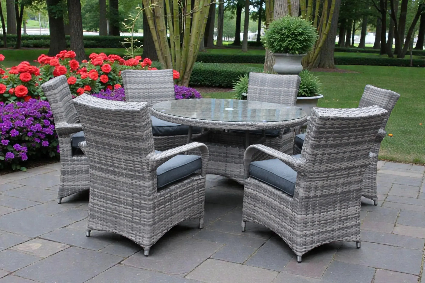 Grey rattan garden dining set with round glass table and cushioned chairs on patio