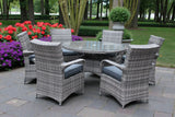 Grey rattan garden dining set with round glass table and cushioned chairs on patio