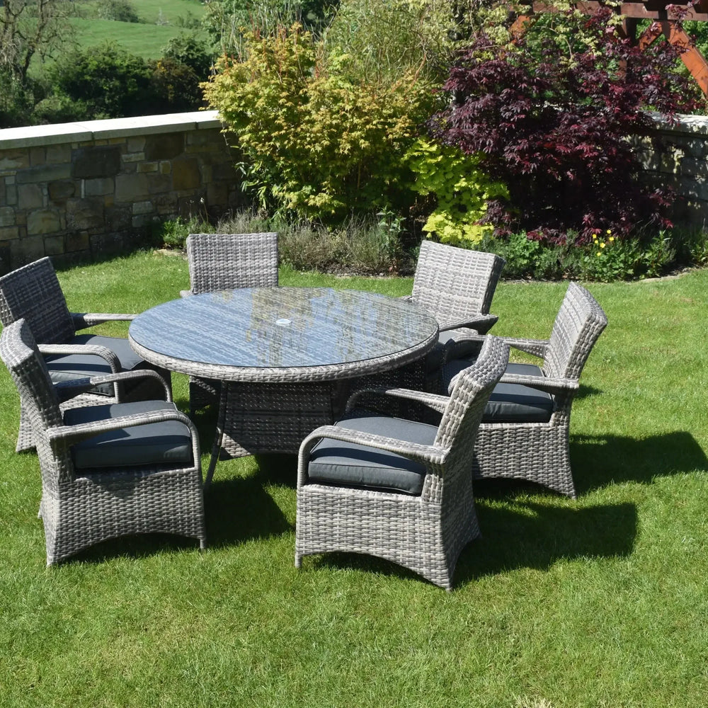 Grey rattan dining set with six cushioned chairs and glass top table on lawn garden