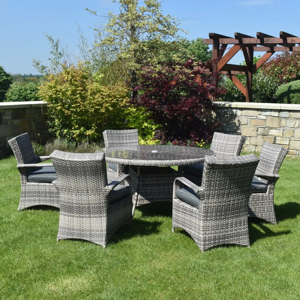 Grey rattan garden dining set with six armchairs and round glass table on lawn