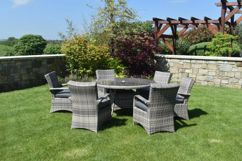 Grey rattan garden dining set with six armchairs and round glass table on lawn