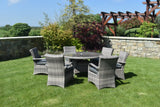 Grey rattan garden dining set with six armchairs and round glass table on lawn