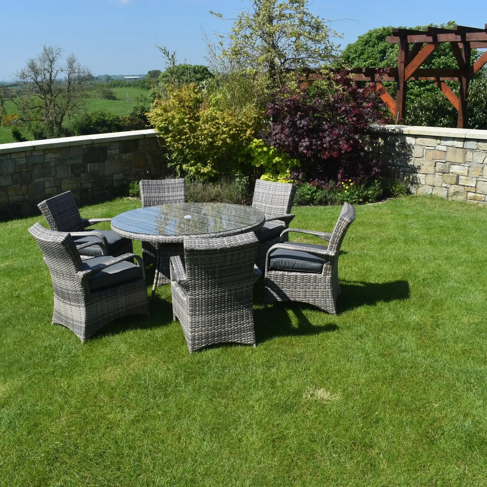 Rattan dining set with glass table and six cushioned chairs on patio lawn