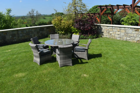 Rattan dining set with glass table and six cushioned chairs on patio lawn