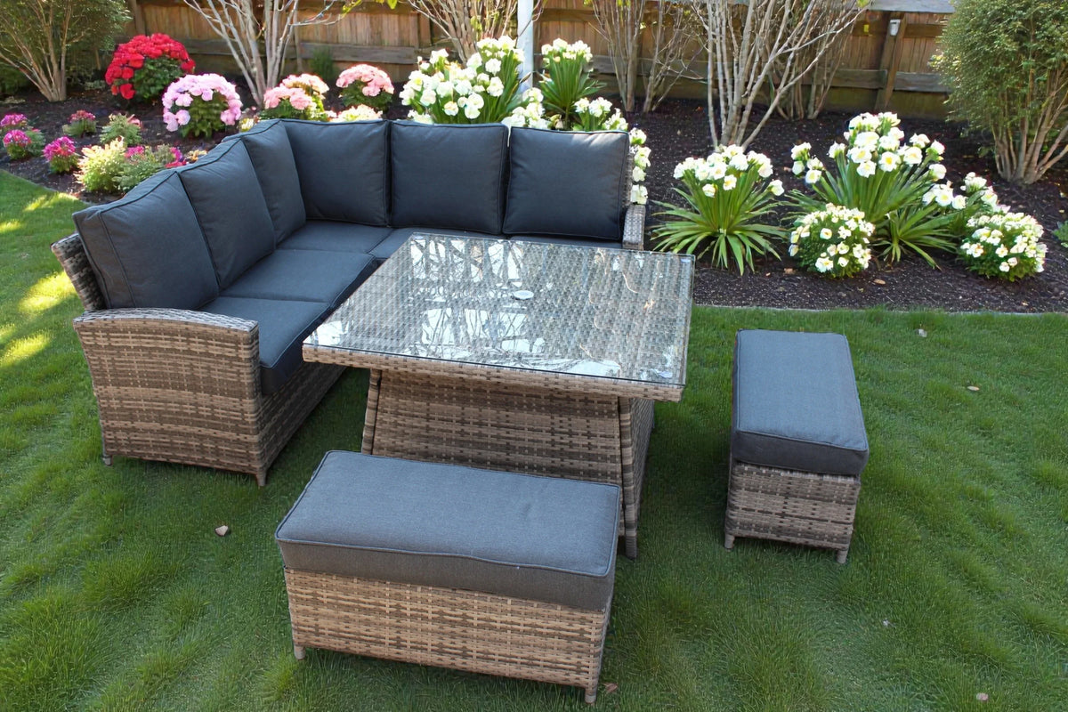 Rattan garden corner set with grey cushions, glass top table and two benches on lawn