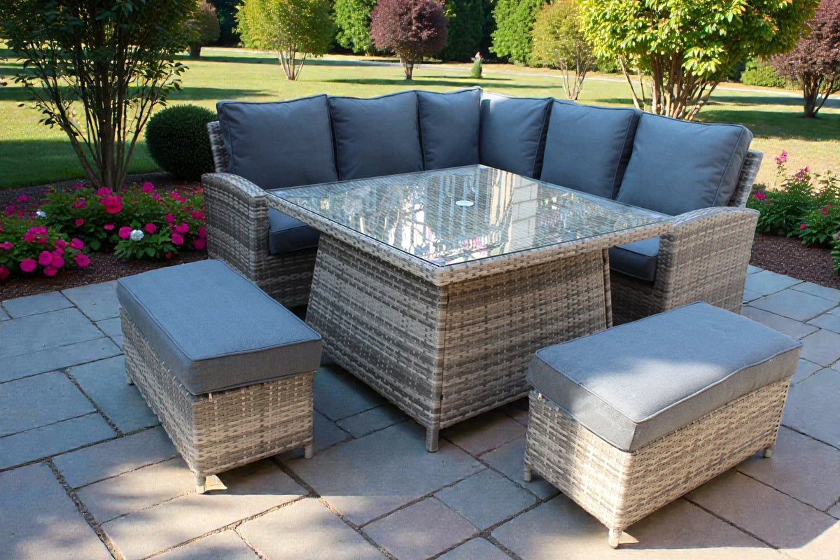 Rattan garden corner sofa set with grey cushions, glass top table, and matching benches on patio