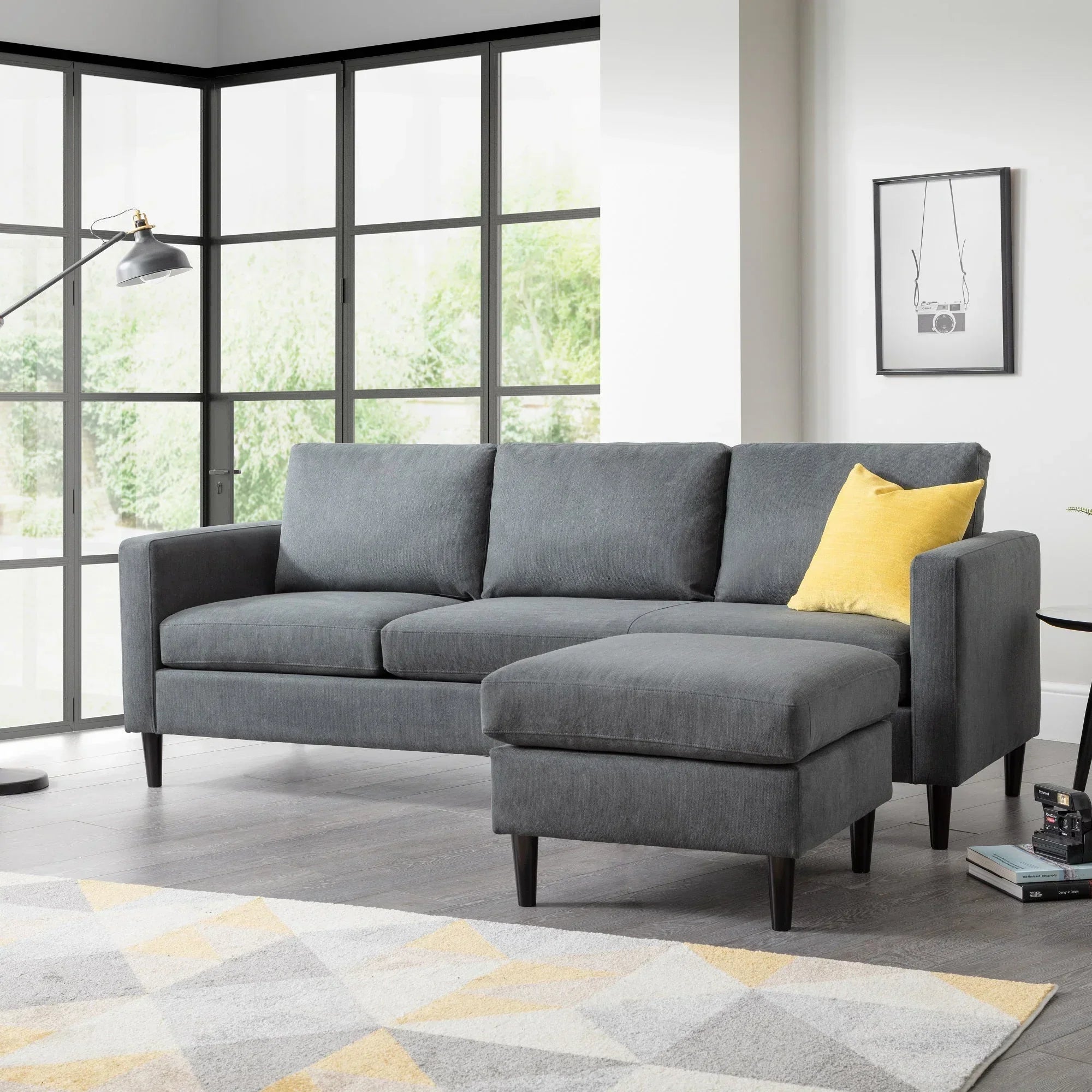 Grey corner sofa with matching ottoman and yellow cushion in modern living room setting