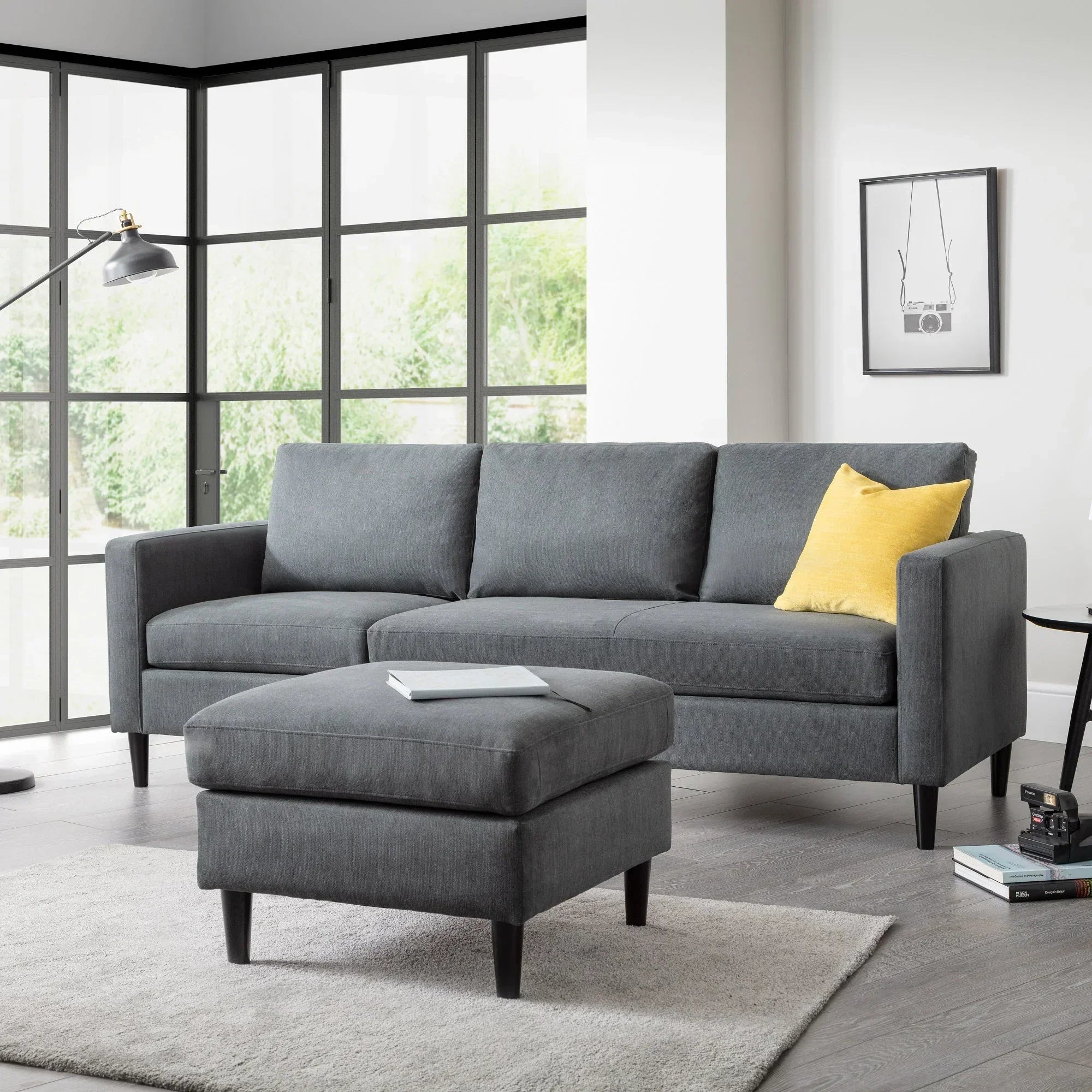 Charcoal corner sofa with ottoman and yellow cushion in modern living room setting