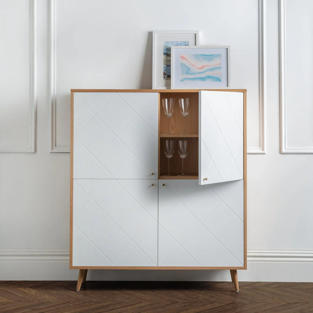 Moritz oak 4 door cabinet with white panels, open section displaying glassware, in modern room