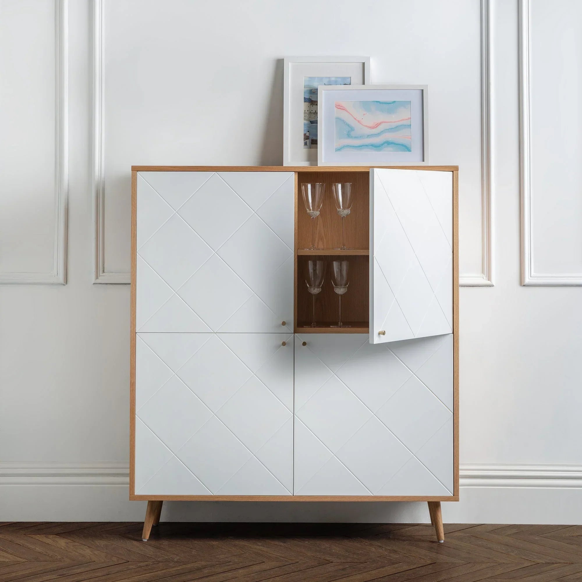 Moritz oak 4 door cabinet with white panels, open section displaying glassware, in modern room