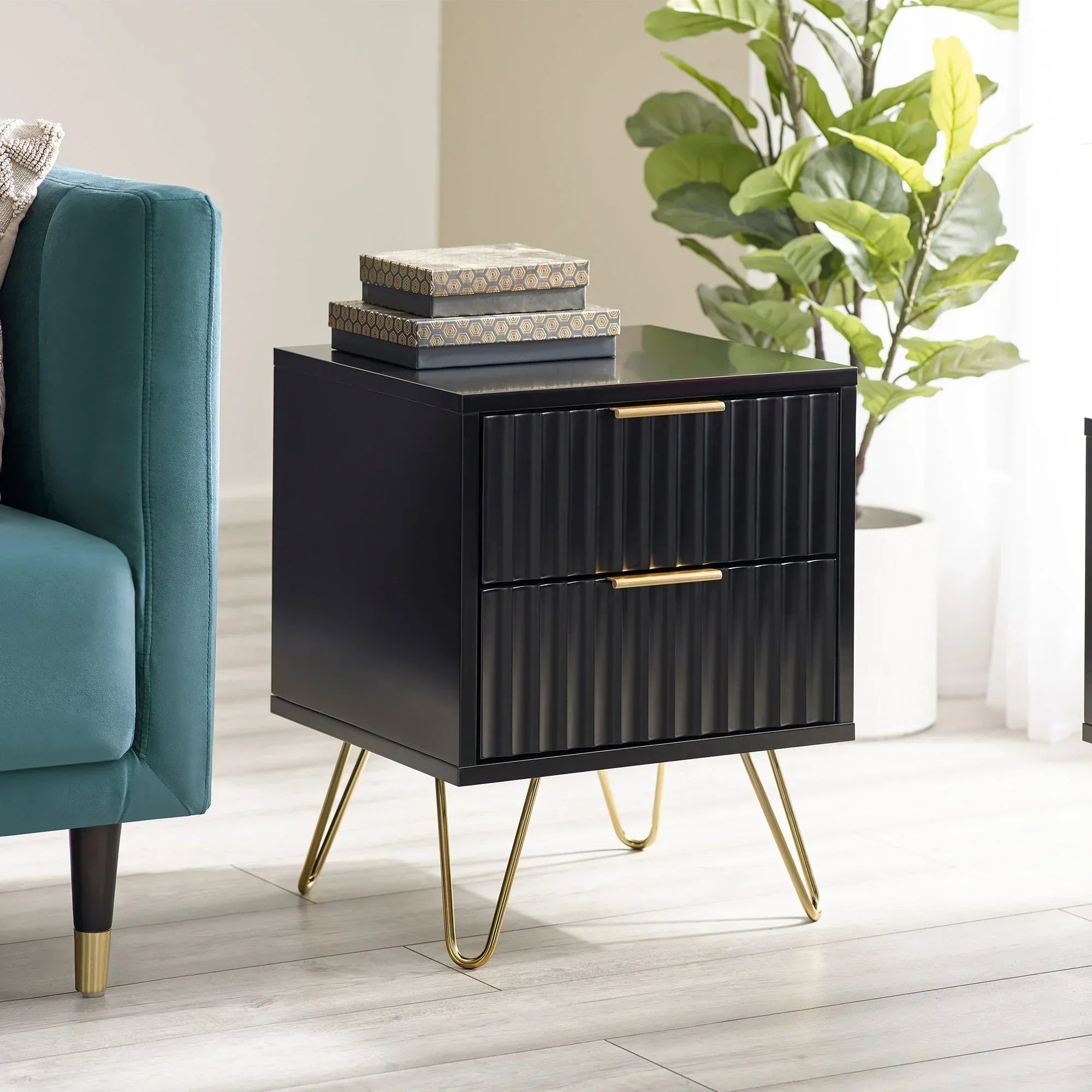Black bedside table with two ribbed drawers, gold handles, and hairpin legs in modern room