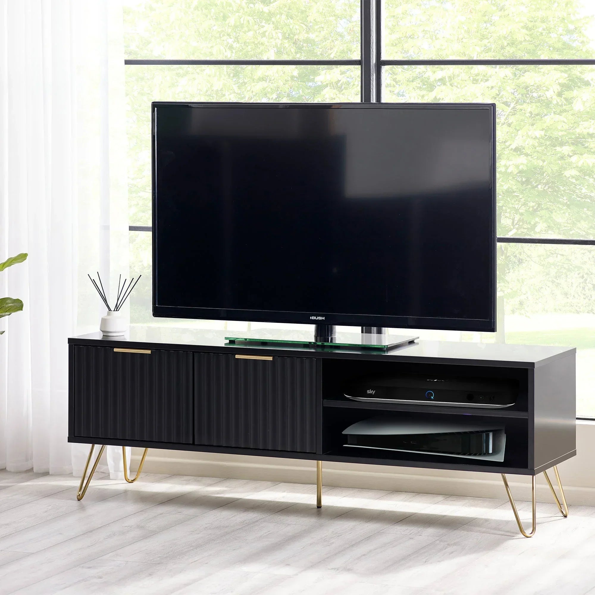 Black TV unit with gold legs and storage shelves in modern living room setting