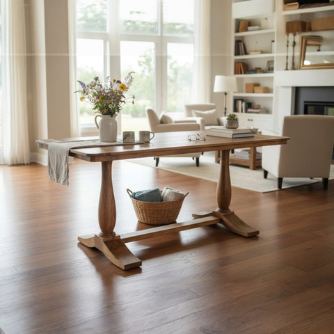 Wooden dining table in a bright living room with large windows and bookshelves.