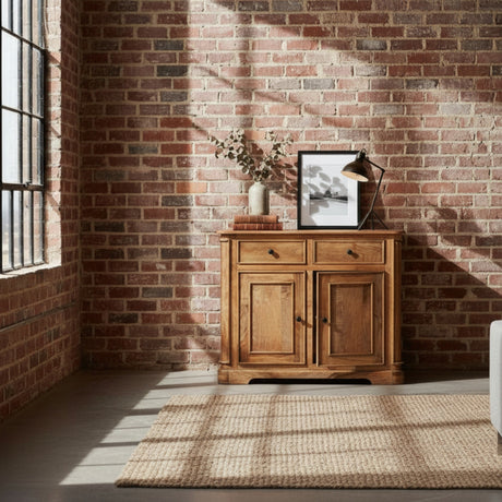 Wooden sideboard against a brick wall with a lamp and framed picture on top