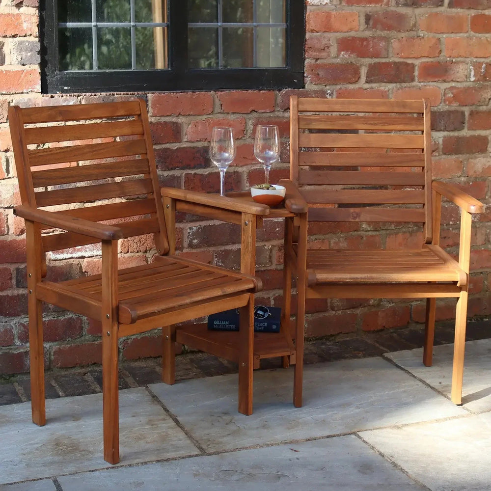 Wooden love seat garden furniture set with built-in table, placed on patio by brick wall