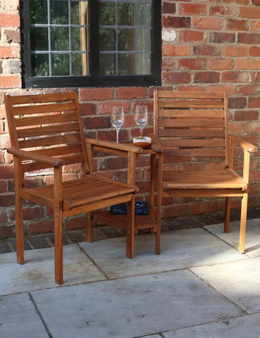 Wooden love seat garden furniture set with built-in table, placed on patio by brick wall