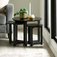 Black wooden nesting tables with plant and candle beside grey sofa on wood floor