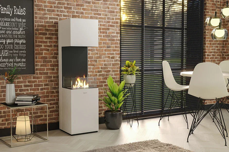 White bioethanol fireplace in modern dining room with brick wall and greenery