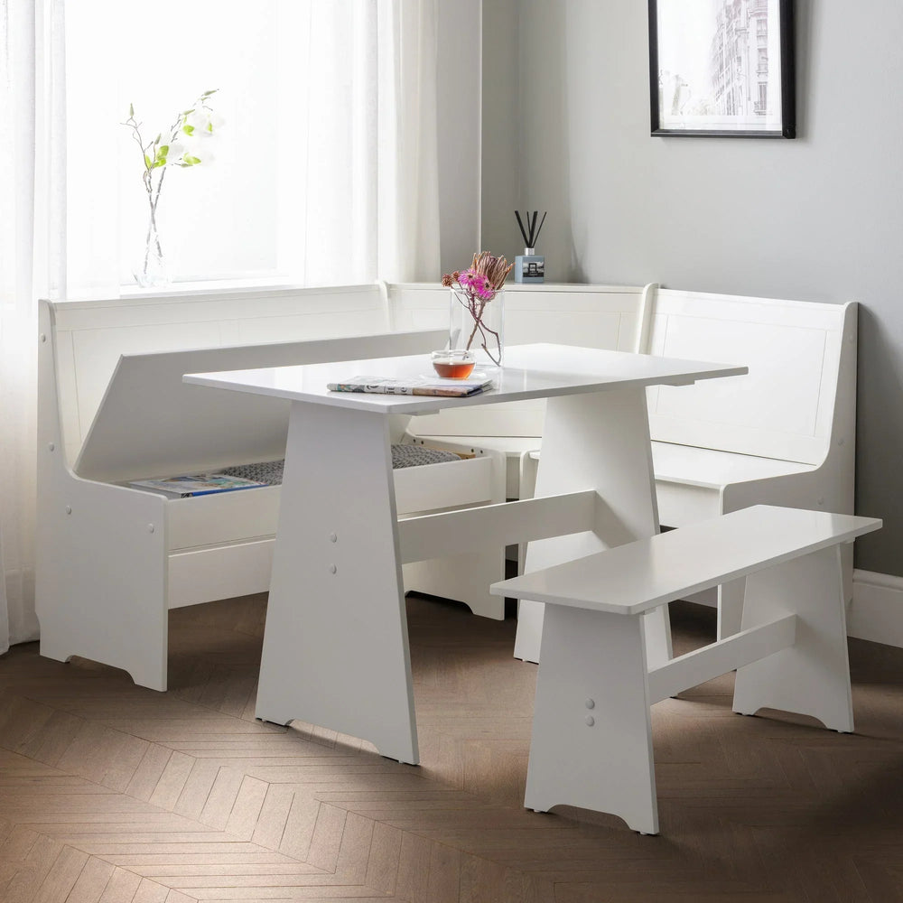 White corner dining set with storage bench in a bright modern dining room